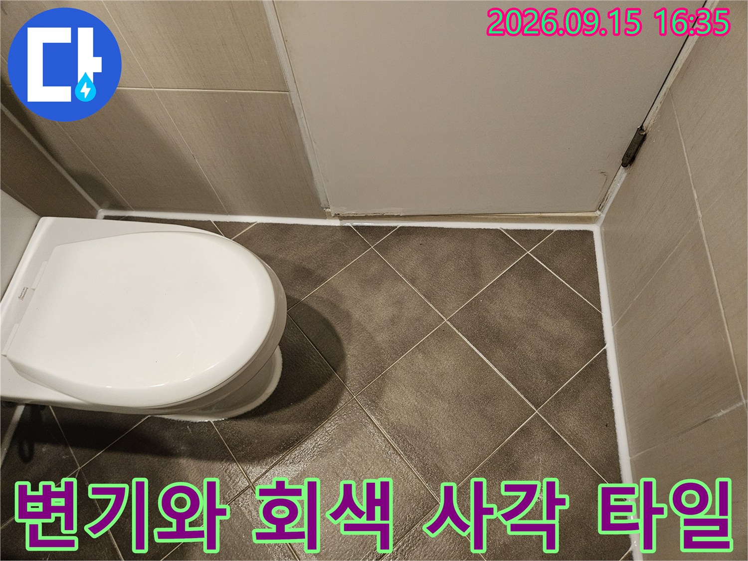 변기 아래쪽의 회색 타일 바닥과 변기 하단을 보여주는 사진입니다.