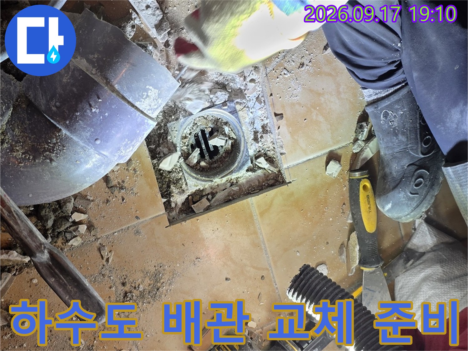 배수구 주변 타일 굴착 후 노출된 배관과 작업용 전동 공구