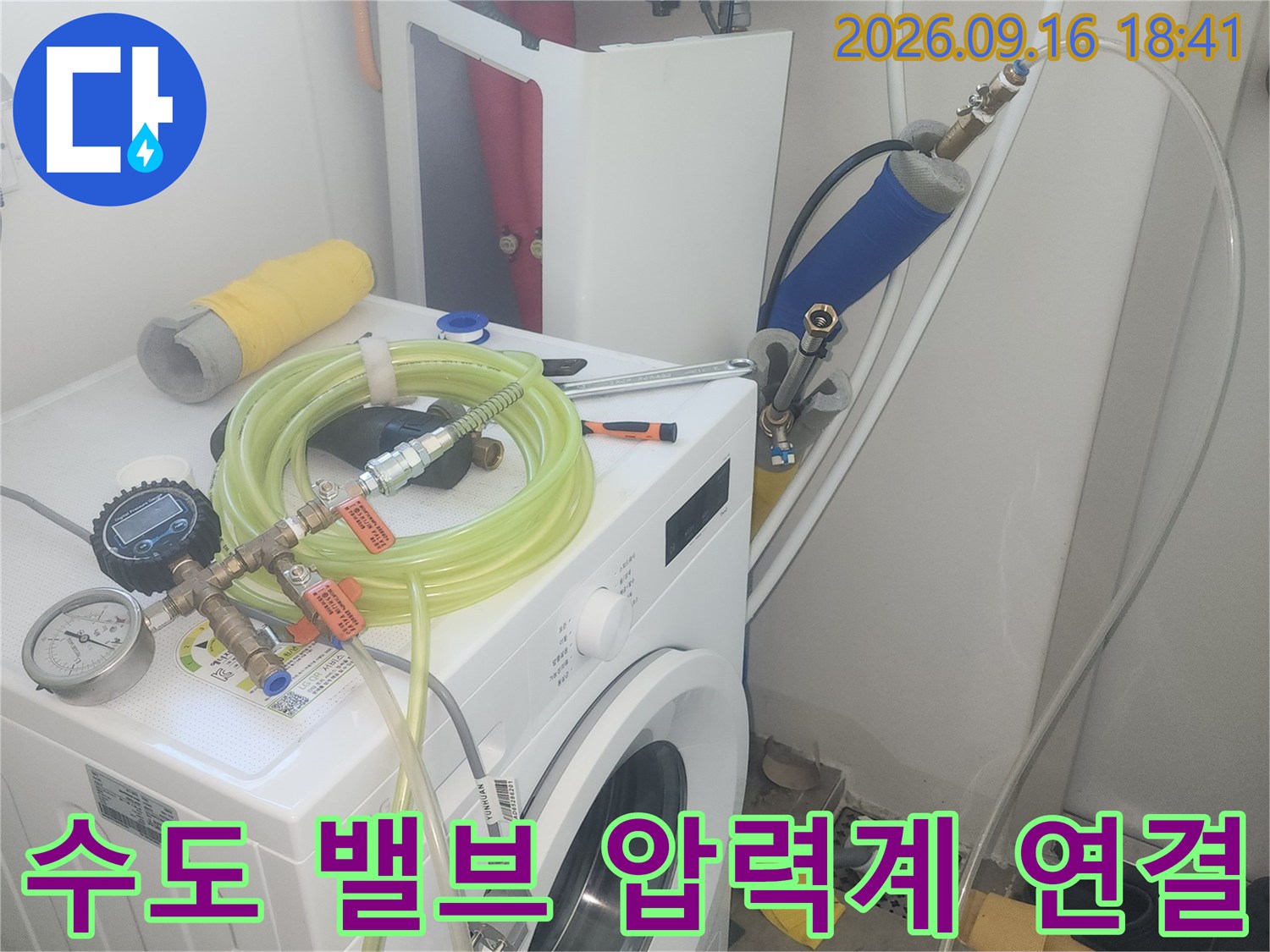 세탁실 벽면 밸브에-압력 측정용 호스와 게이지를 연결하여 검사 중입니다.