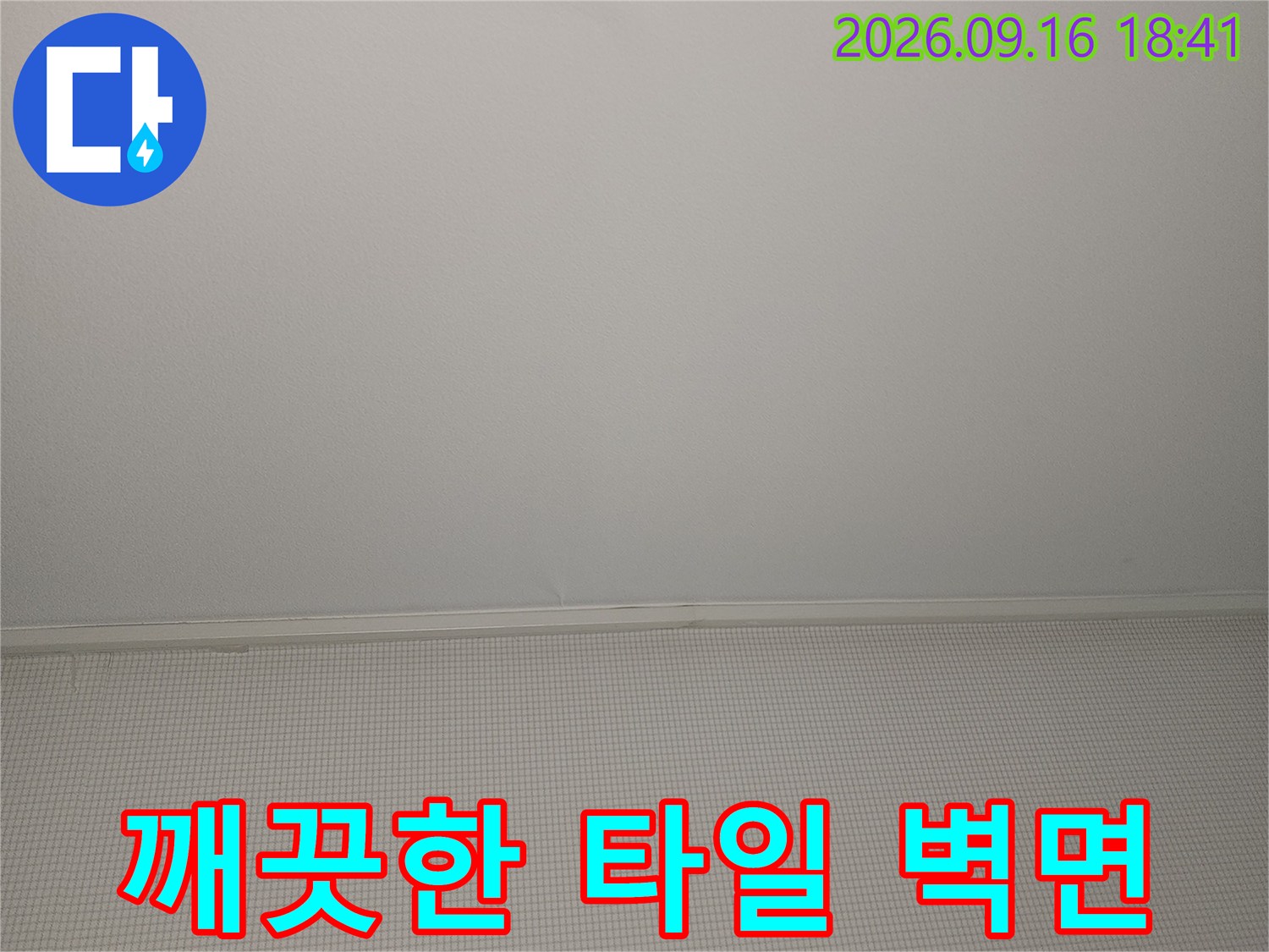 정리가 잘 된 화장실의 하얀색 타일 벽면 모습입니다.