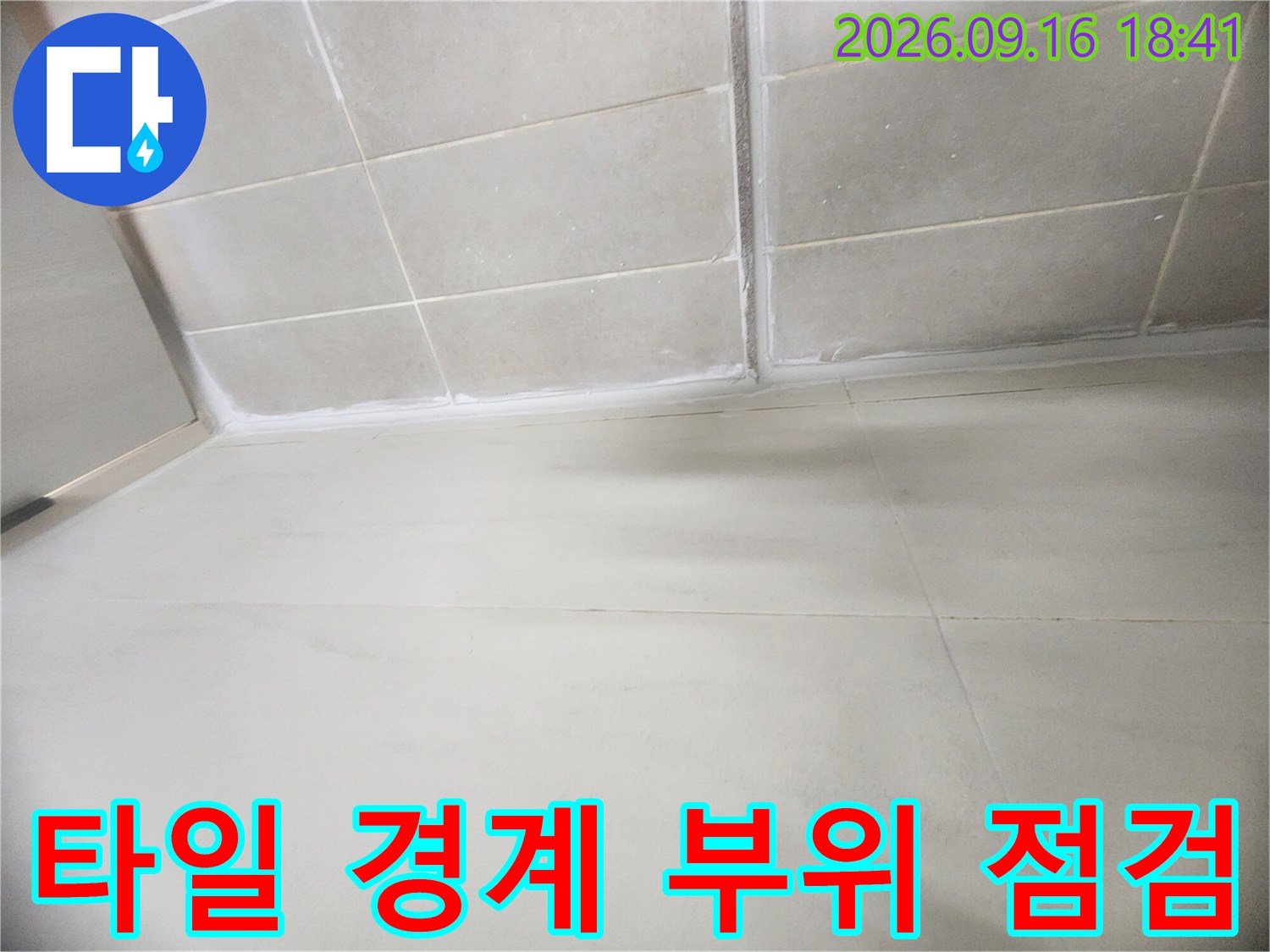 하얀색 타일 벽면과 바닥이 만나는 지점의 메지 상태를 촬영한 사진입니다.