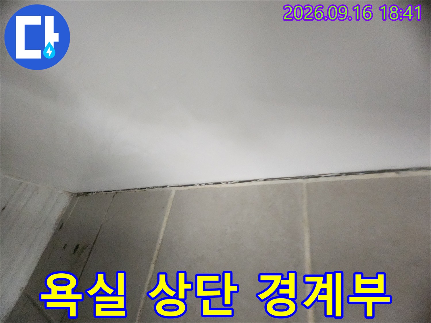 화장실의 하얀색 천장과 타일이 만나는 지점의 근접 사진입니다.