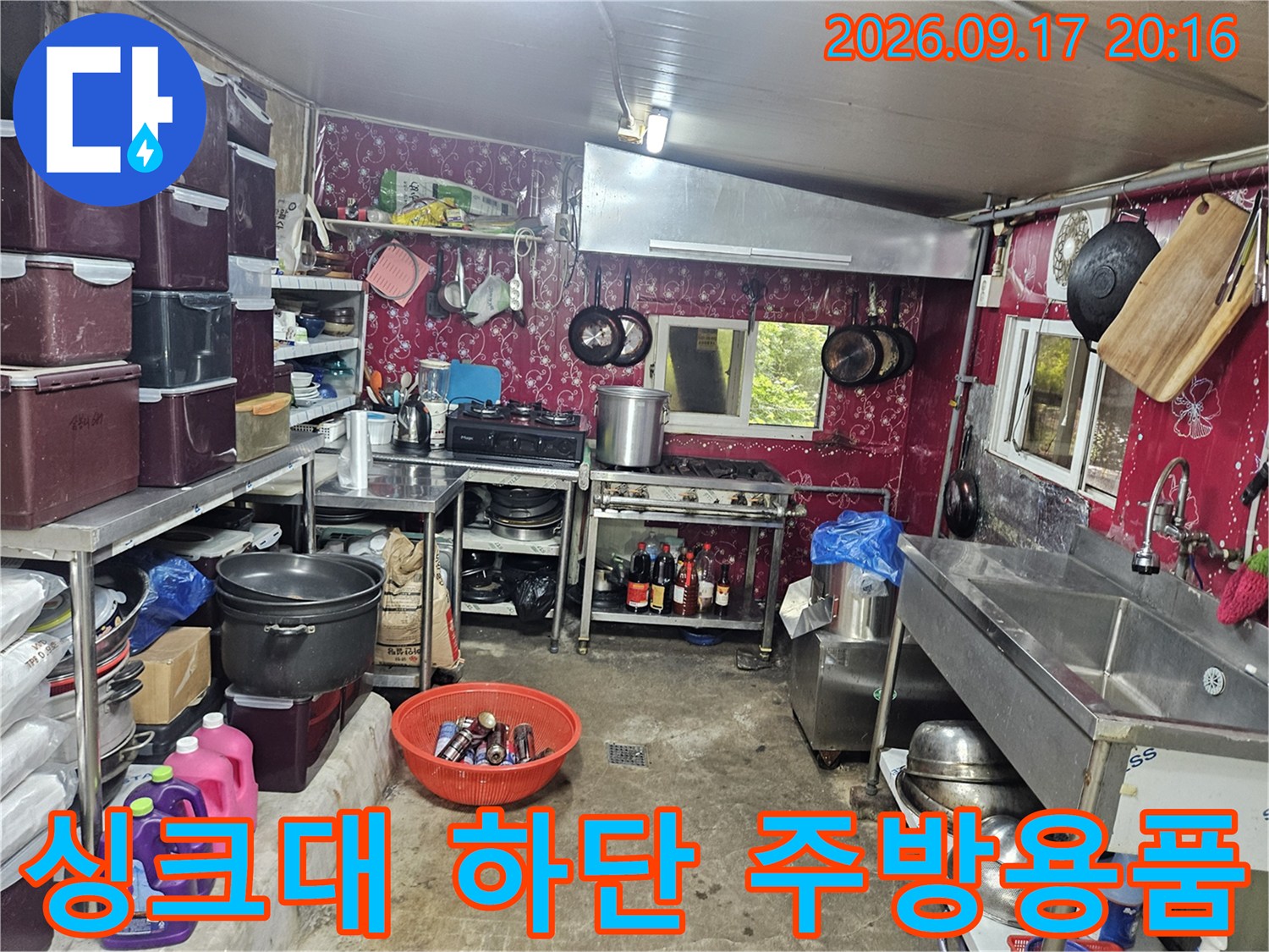 주방 싱크대 아래쪽의 수납된 용기들과 배관 주변 모습