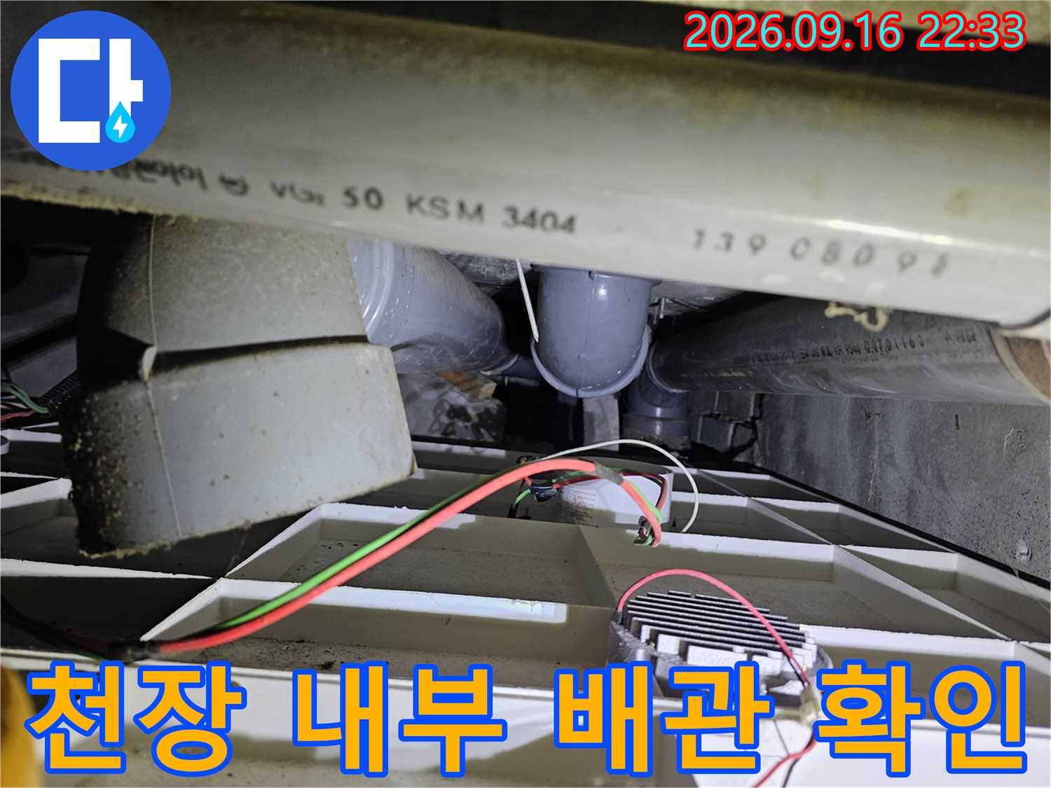 천장 점검구 내부에 보이는 굵은 배관과 전기 선들의 모습입니다.