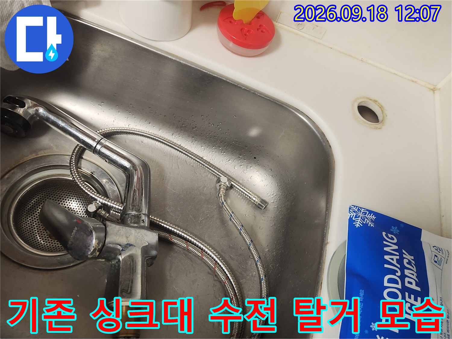 싱크볼에 설치된 은색 수전과 연결 호스의 상태를 보여줍니다.